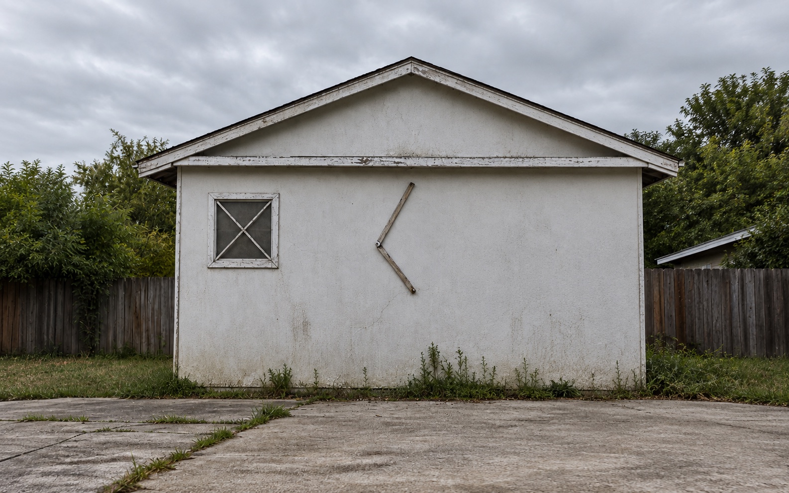 Same home before renovation, worn stucco siding and an aging window frame